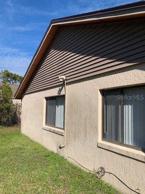 view of side of property with stucco siding and a yard