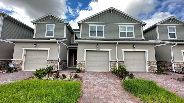 craftsman-style house with board and batten siding, stone siding, and driveway