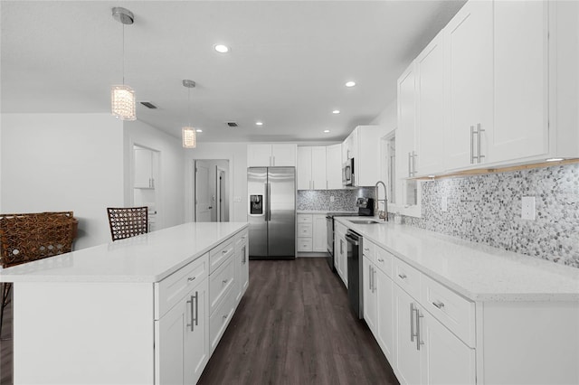 kitchen featuring a kitchen island, appliances with stainless steel finishes, pendant lighting, white cabinetry, and decorative backsplash