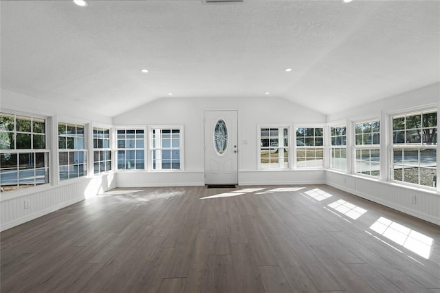 unfurnished living room featuring vaulted ceiling, dark wood-type flooring, and a textured ceiling