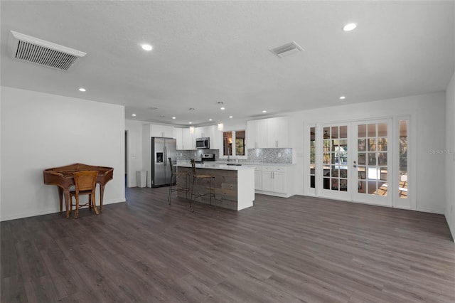 kitchen featuring appliances with stainless steel finishes, backsplash, white cabinets, a kitchen island, and dark hardwood / wood-style flooring