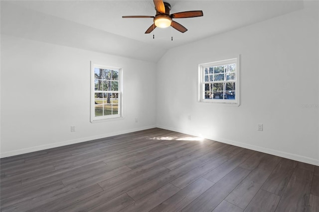 empty room featuring vaulted ceiling, dark wood-type flooring, a wealth of natural light, and ceiling fan