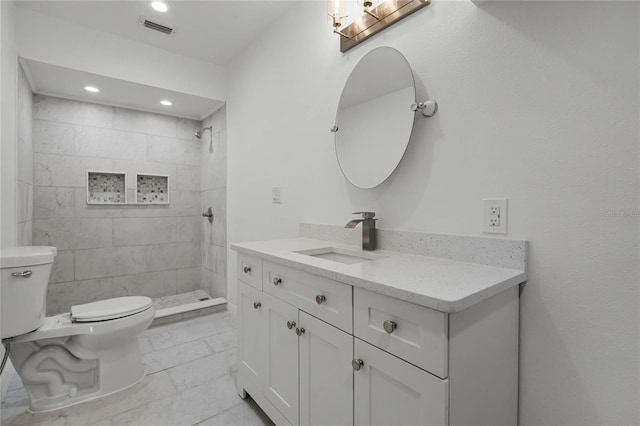 bathroom with vanity, toilet, and a tile shower