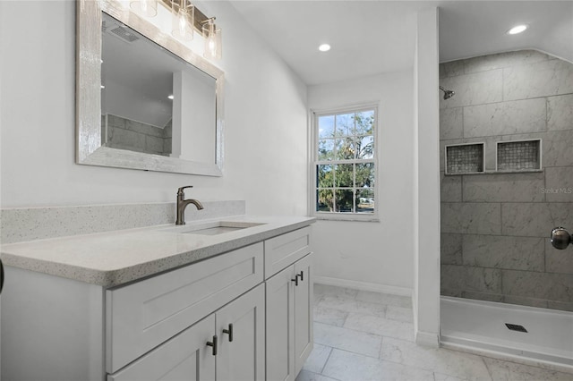 bathroom with vanity and a tile shower