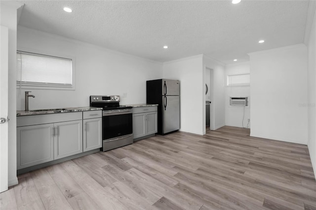 kitchen with sink, gray cabinetry, light wood-type flooring, stainless steel appliances, and a textured ceiling