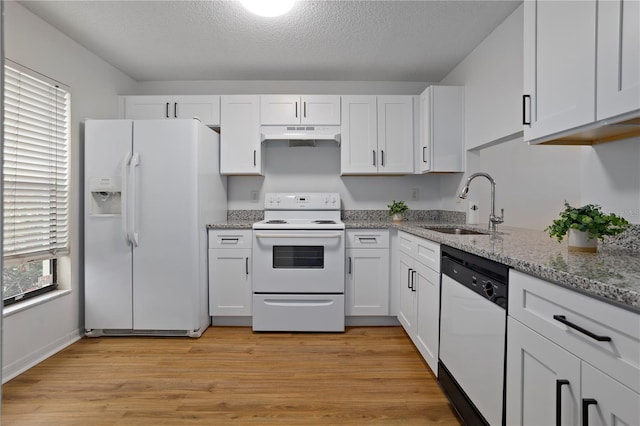 kitchen with under cabinet range hood, white appliances, a sink, white cabinets, and light wood finished floors