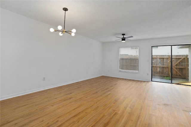 empty room featuring light wood-style floors, baseboards, a textured ceiling, and ceiling fan with notable chandelier