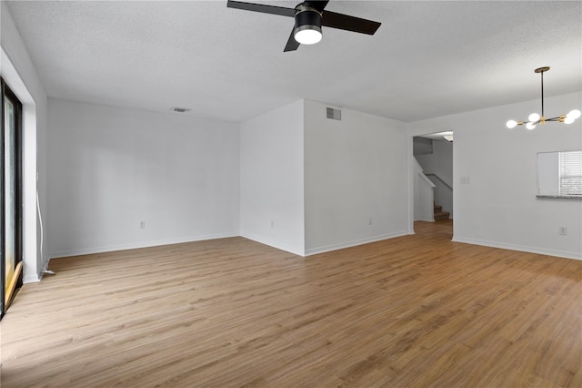 unfurnished room featuring stairs, a textured ceiling, visible vents, and light wood-style floors