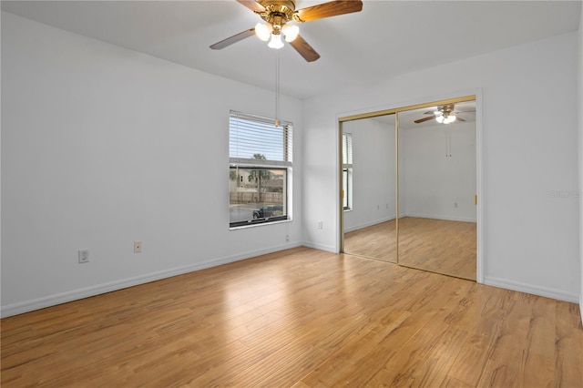 unfurnished bedroom with light wood-type flooring, a closet, ceiling fan, and baseboards