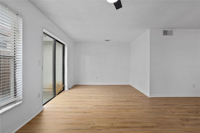 spare room with light wood-type flooring, visible vents, and a wealth of natural light