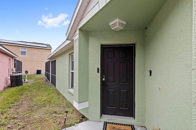 property entrance featuring central AC unit and a yard