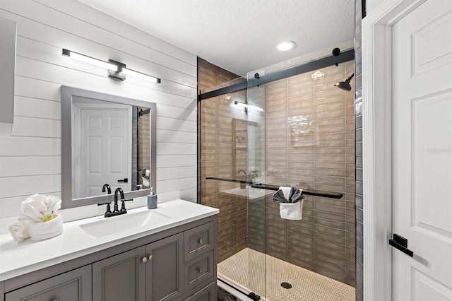 bathroom featuring vanity, wood walls, a textured ceiling, and an enclosed shower