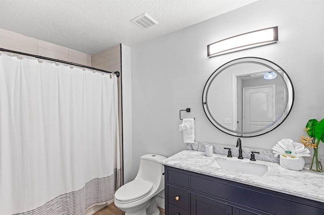 bathroom featuring toilet, a textured ceiling, a shower with shower curtain, and vanity