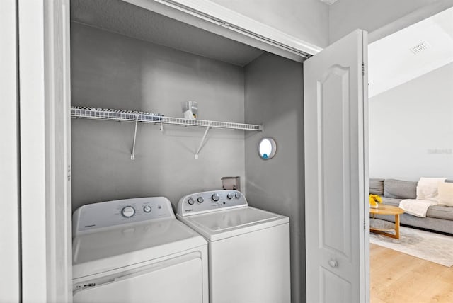 clothes washing area with light hardwood / wood-style flooring and washing machine and clothes dryer