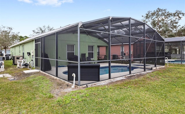 rear view of property with a patio, glass enclosure, and a lawn