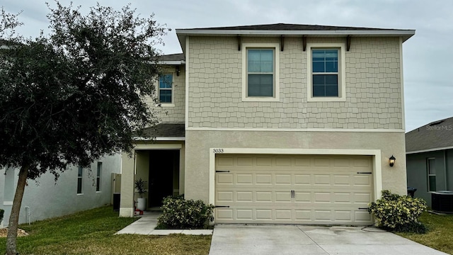 view of property featuring a front yard, a garage, and central air condition unit