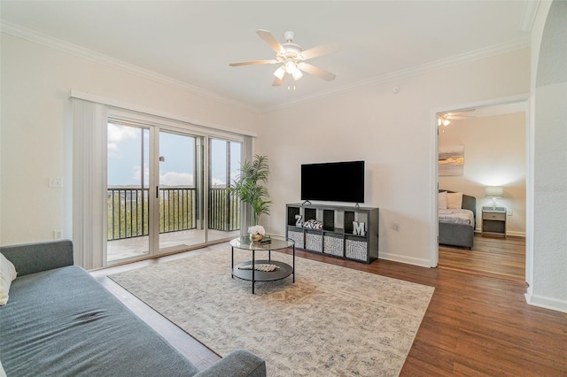 living room featuring dark wood-type flooring, ceiling fan, and crown molding