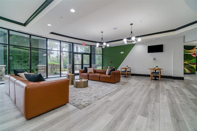 living room featuring floor to ceiling windows, a tray ceiling, a chandelier, and light hardwood / wood-style flooring