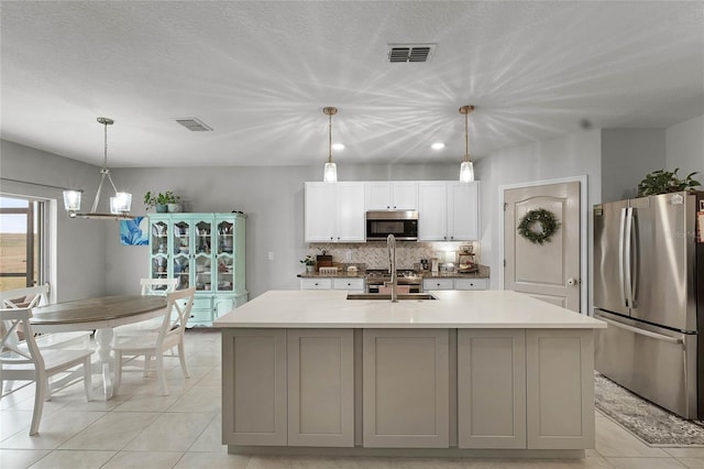 kitchen featuring sink, a center island with sink, tasteful backsplash, and stainless steel fridge