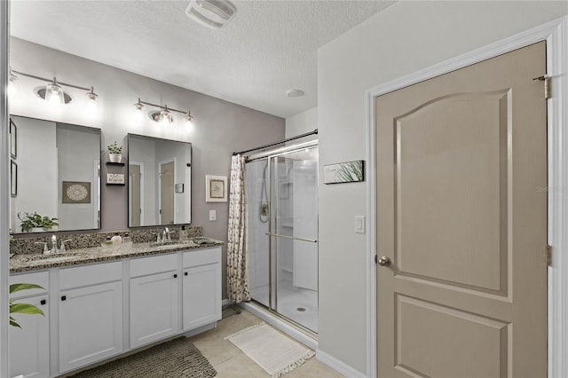 bathroom with vanity, walk in shower, a textured ceiling, and tile patterned flooring