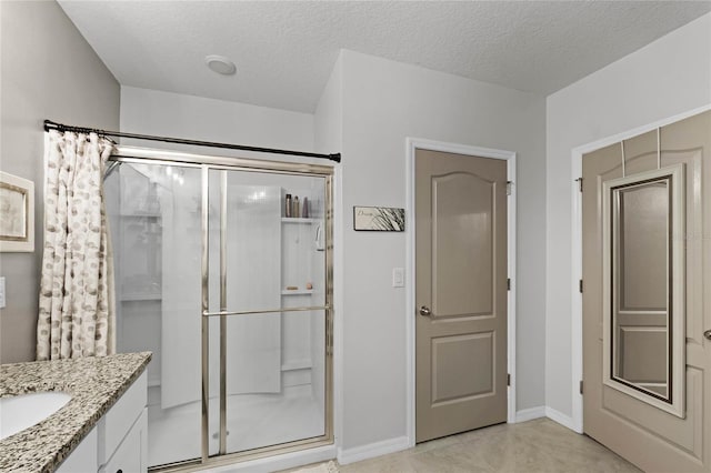 bathroom with vanity, tile patterned floors, a textured ceiling, and a shower with door