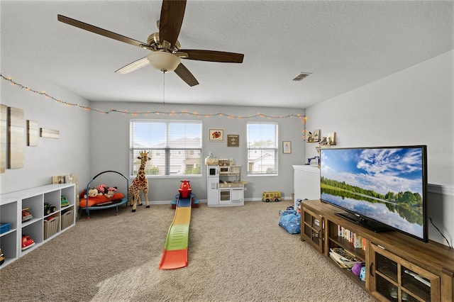 recreation room with carpet floors, a textured ceiling, and ceiling fan