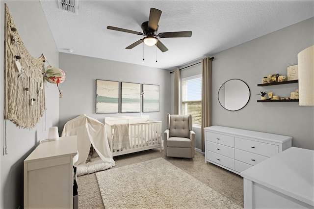 bedroom with ceiling fan, a textured ceiling, and a nursery area