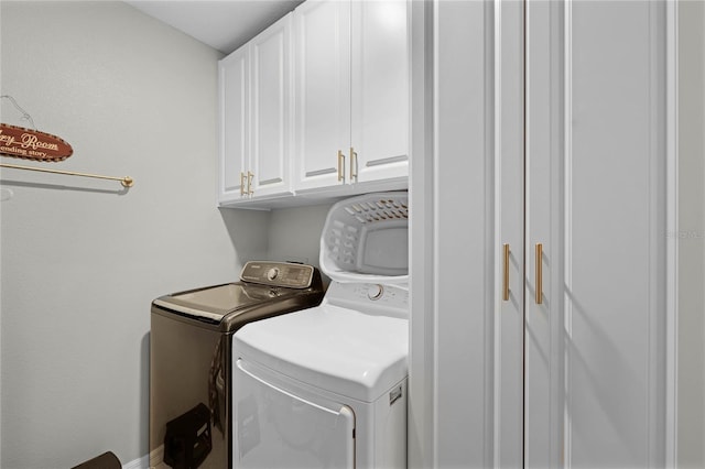 clothes washing area featuring cabinets and washer and clothes dryer