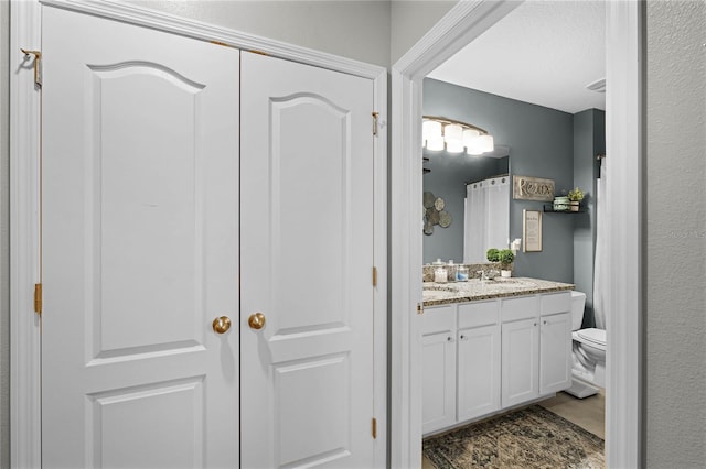 bathroom with toilet, a shower with shower curtain, and vanity