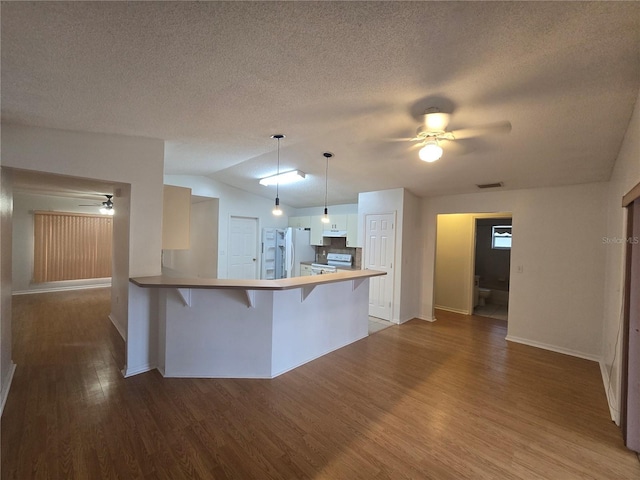 kitchen featuring decorative light fixtures, hardwood / wood-style floors, kitchen peninsula, range with electric stovetop, and a breakfast bar area