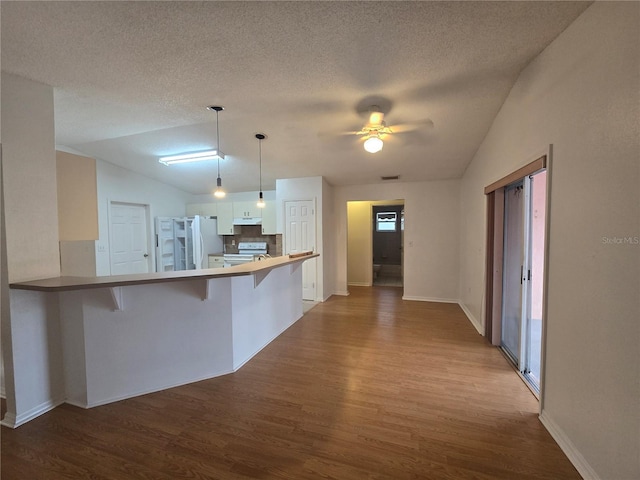 kitchen featuring pendant lighting, white appliances, white cabinetry, a kitchen breakfast bar, and kitchen peninsula