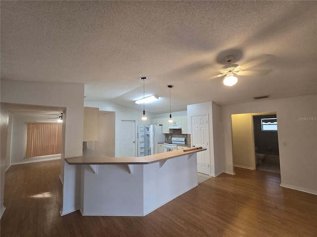 kitchen with a kitchen bar, decorative light fixtures, white range with electric cooktop, refrigerator, and kitchen peninsula