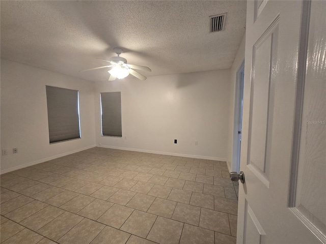 empty room with ceiling fan, a textured ceiling, and light tile patterned floors