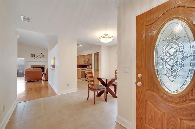 foyer featuring lofted ceiling, light tile patterned floors, and a wealth of natural light