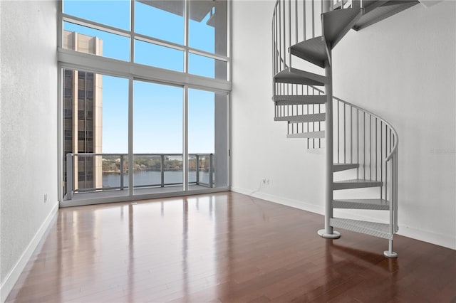 stairway with a high ceiling, wood-type flooring, and a water view