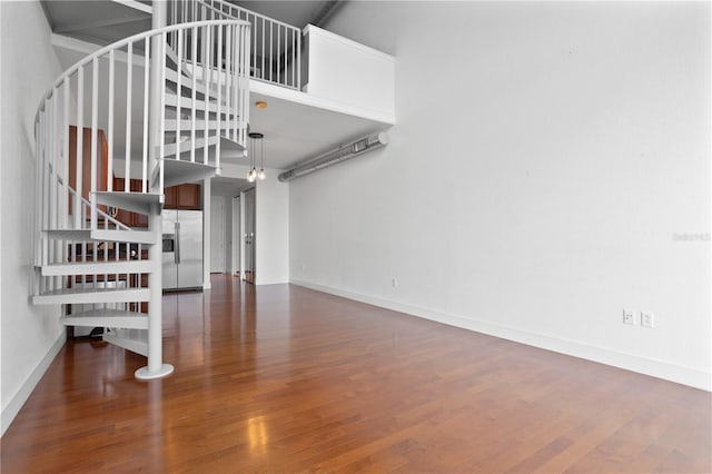 stairway featuring wood-type flooring and a towering ceiling