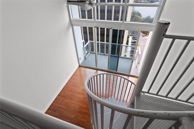 stairs with ceiling fan, wood-type flooring, and a towering ceiling