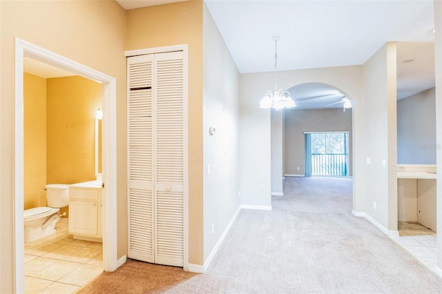 corridor featuring light carpet and a chandelier