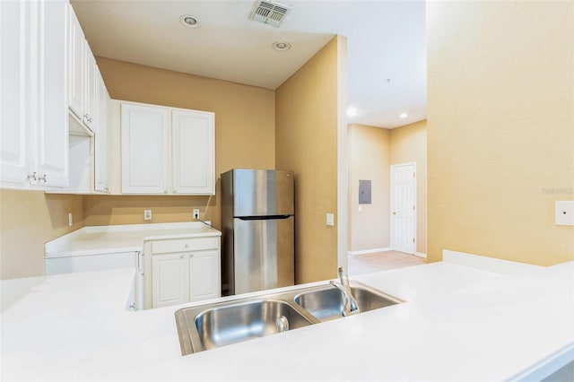 kitchen with kitchen peninsula, stainless steel fridge, sink, and white cabinetry