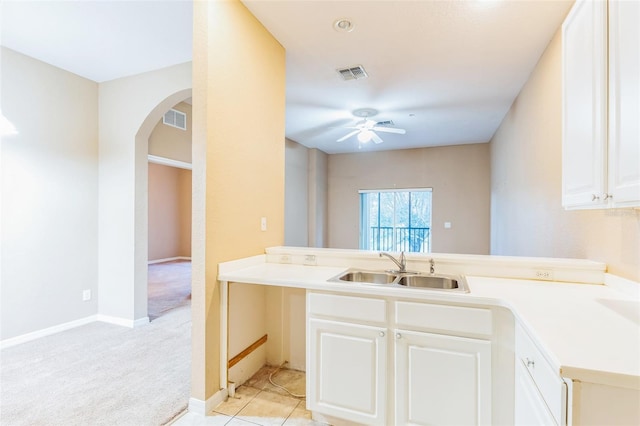 kitchen featuring light colored carpet, kitchen peninsula, sink, and white cabinetry