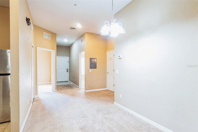 spare room featuring light carpet, a chandelier, and electric panel