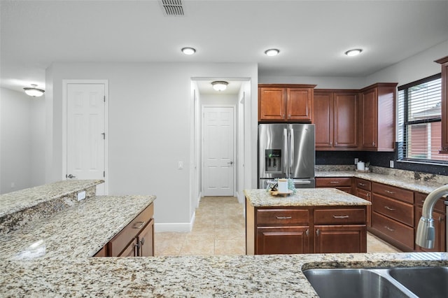 kitchen with sink, light stone counters, light tile patterned floors, and stainless steel refrigerator with ice dispenser