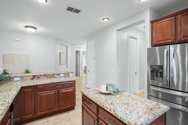 kitchen with light stone countertops, light tile patterned floors, stainless steel appliances, and a kitchen island