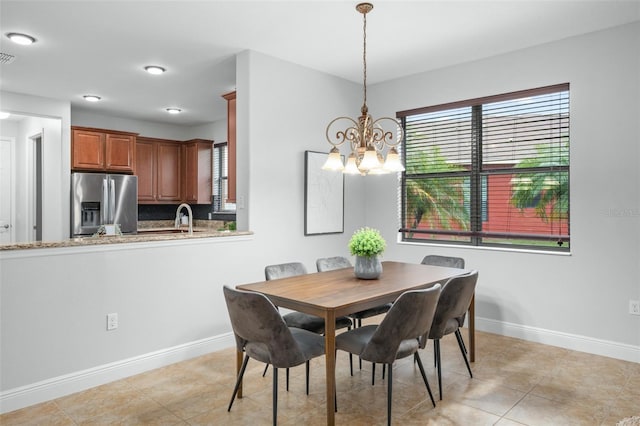 dining area with sink, light tile patterned floors, and a notable chandelier