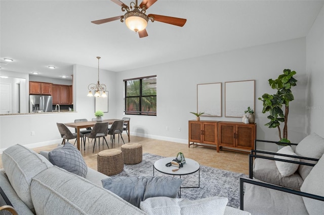 tiled living room with ceiling fan with notable chandelier