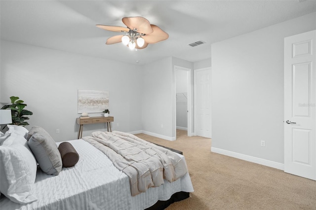 bedroom with ceiling fan, light colored carpet, a closet, and a walk in closet