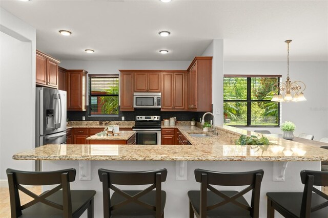800 Ebb Tide Ln, Kissimmee, FL 34759 - kitchen featuring a notable chandelier, light stone counters, a sink, a peninsula, and stainless steel appliances