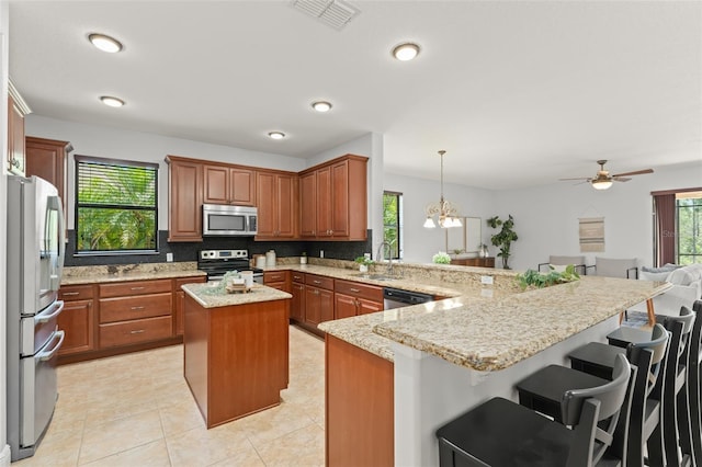 800 Ebb Tide Ln, Kissimmee, FL 34759 - kitchen with stainless steel appliances, a sink, visible vents, a peninsula, and brown cabinetry