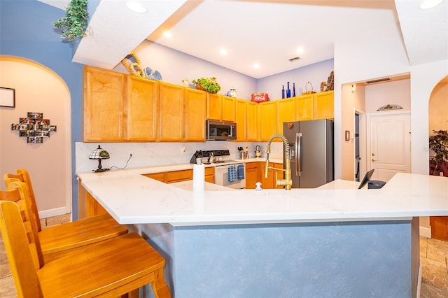 kitchen with kitchen peninsula, stainless steel appliances, a kitchen island with sink, a kitchen breakfast bar, and sink