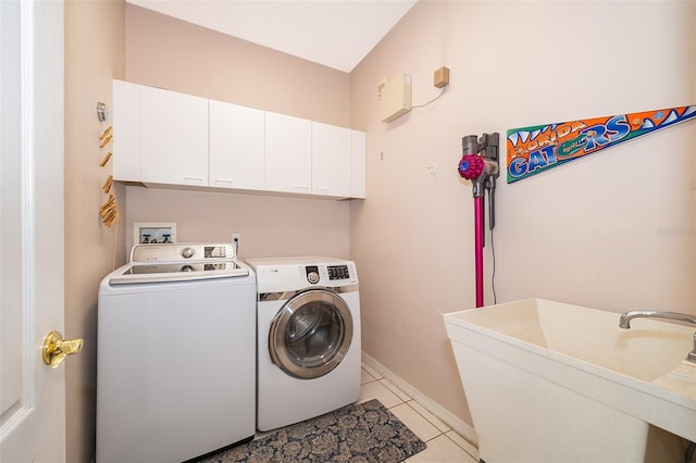 clothes washing area with washer and dryer, light tile patterned flooring, sink, and cabinets